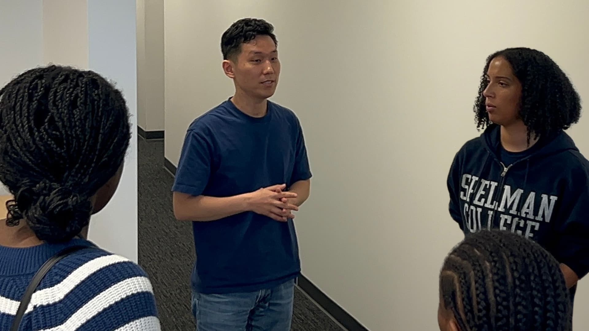 A group of casually dressed people speak in a hallway