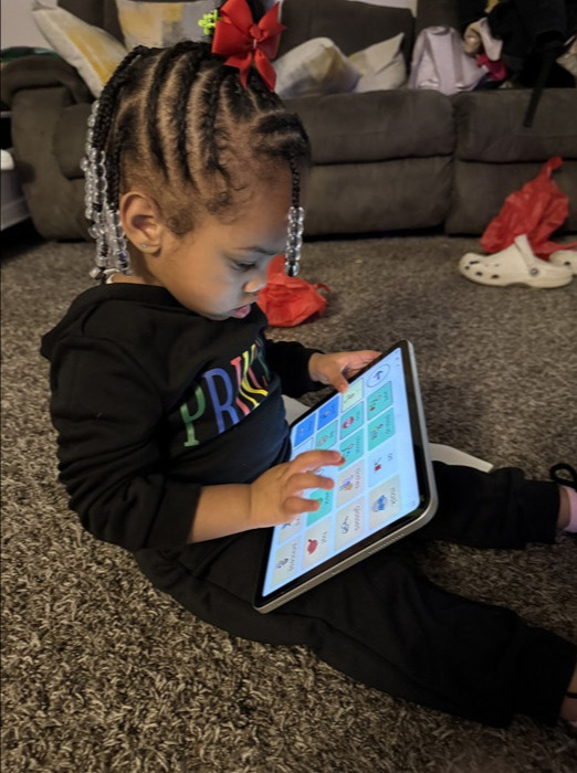 a child sitting on the floor using an aac device